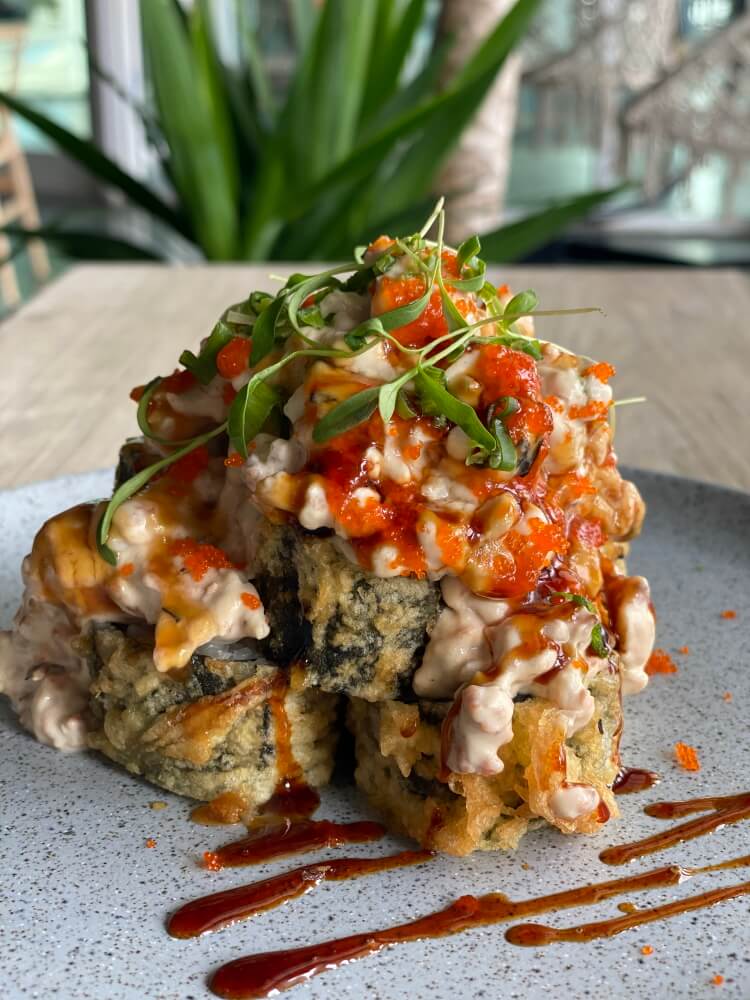 VOLCANO ROLL in North Miami, Floridad - Salmon, cream cheese and masago deep fried in tempura batter. Covered with gratin salmon in a cheesy sauce - Arigatai Sushi Restaurant
